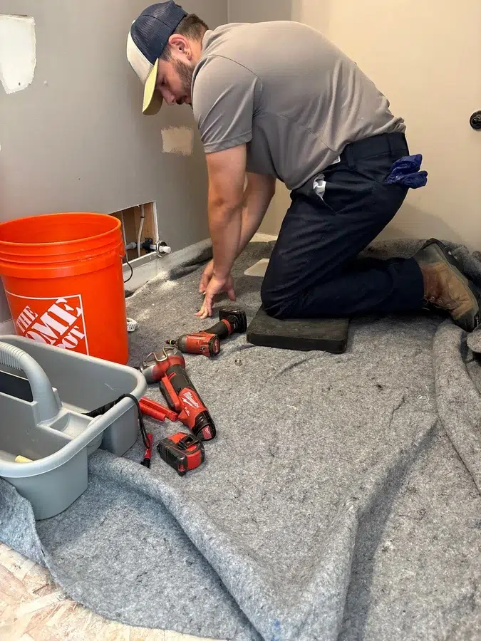 pittsburgh plumber performing leak detection services using a drop cloth