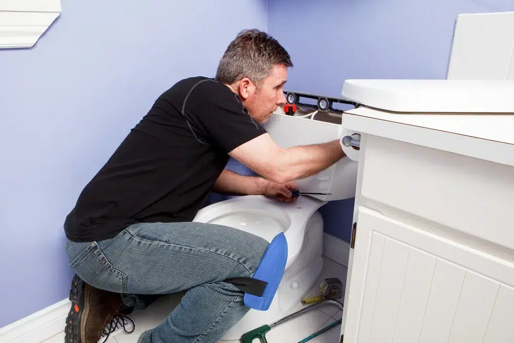 Plumber repairing toilet in Pittsburg, PA.