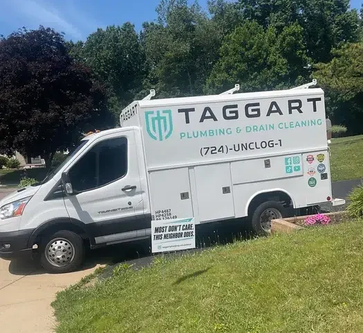 White Taggart Plumbing service van with green logo and phone number parked on a driveway in Freedom, PA