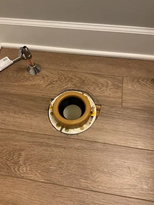 New brass toilet flange set into hardwood flooring during a toilet repair and reset in Allison Park, PA